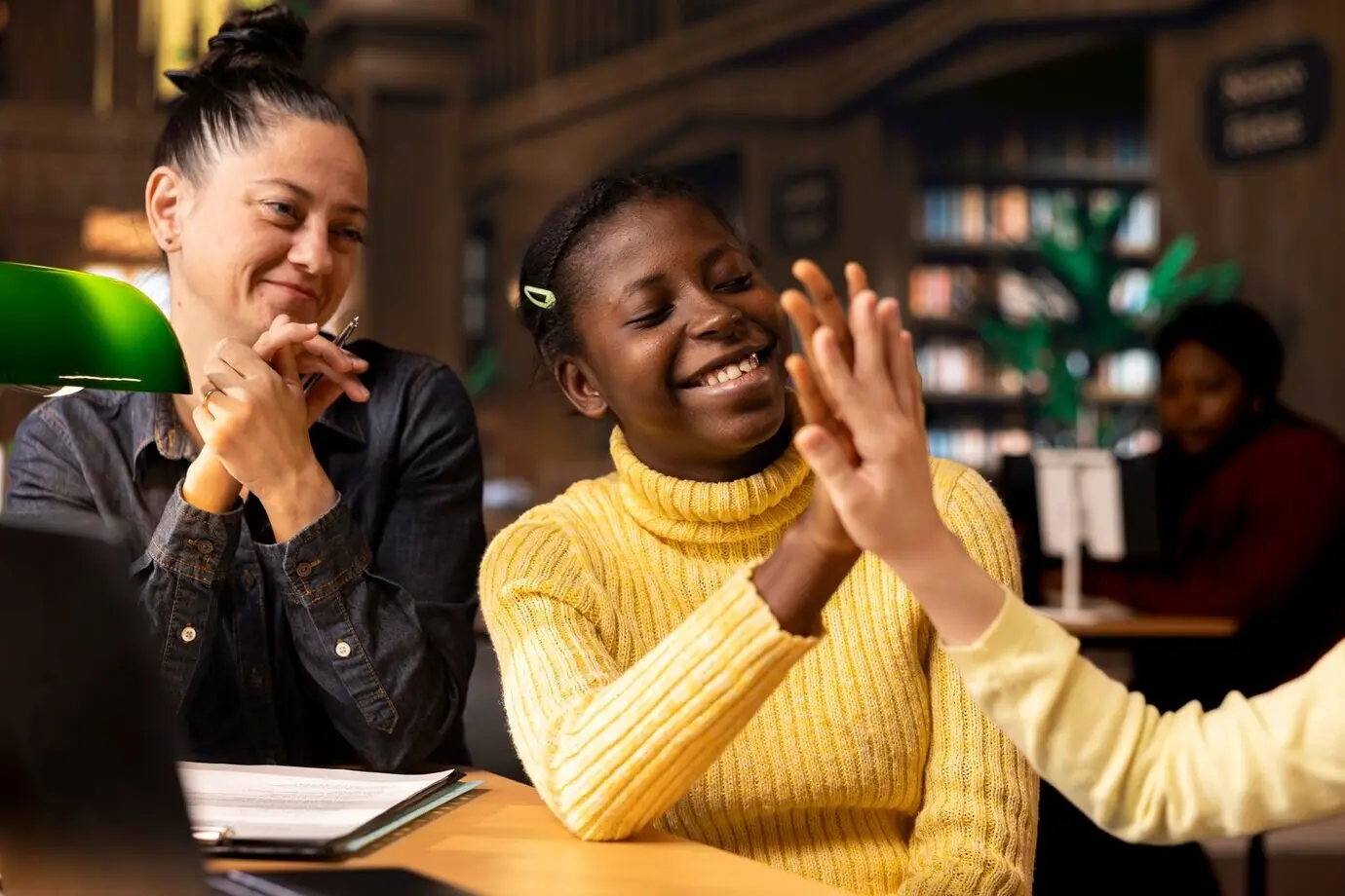 Разнообразные ученики-подростки делают жест «дай пять» в конце занятия с репетитором.