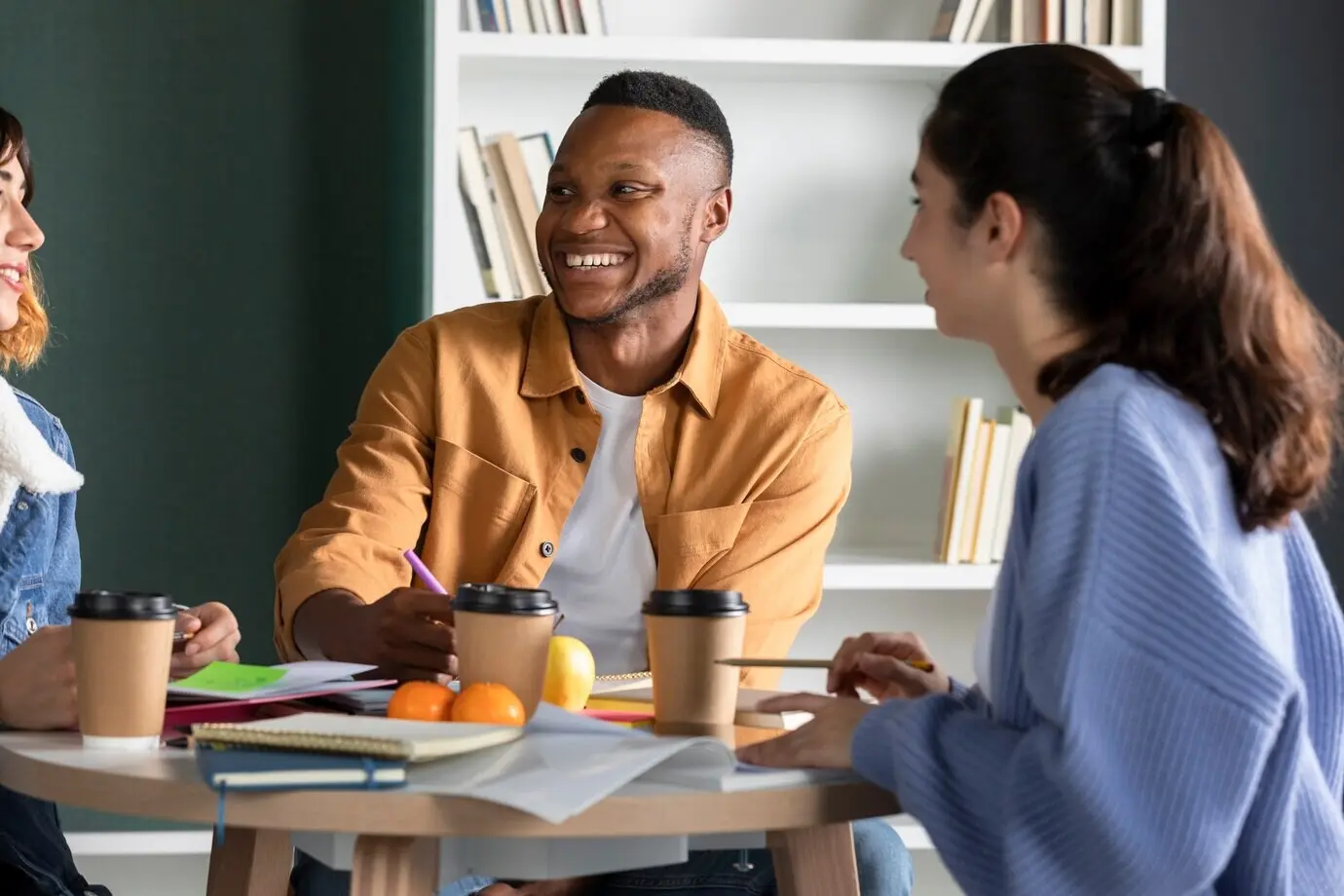 Молодой человек разговаривает с друзьями и делает заметки во время учебного занятия.